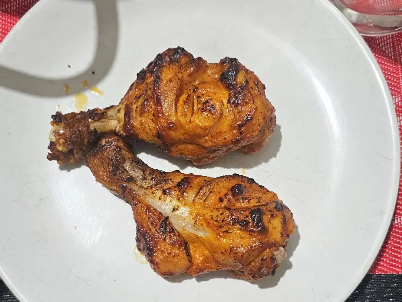 Twee stukken halve gegrilde kip, goudbruin gegrild, geserveerd op een bord