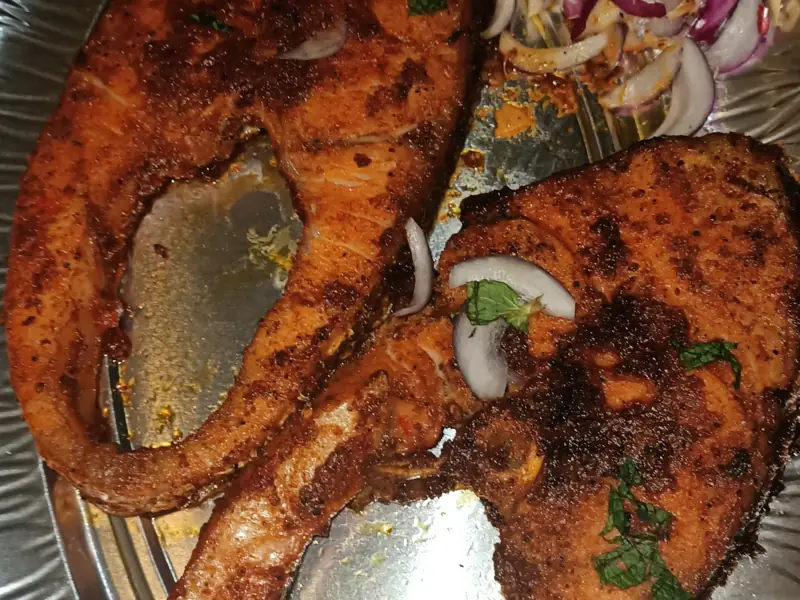 Two spiced salmon steaks, pan-fried, with sliced red onion and mint